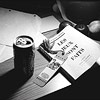 A desk with fruits, a closed french book, bookmark, can of soda, paper...