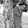 Woman in dress hides behind tree in manhattan