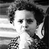 Toddler standing holding milk bottle seriously.